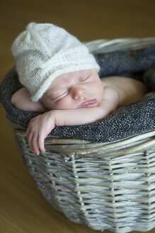 Portrait of sleeping newborn in a wickerbasket wearing wooly hat - JTLF000031