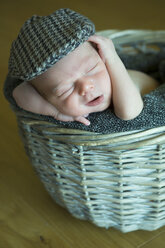 Porträt eines schlafenden Neugeborenen in einem Weidenkorb mit Mütze - JTLF000032