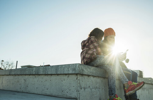 Two girls in skatepark sharing cell phone - UUF003036