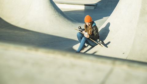 Teenager-Mädchen mit Handy im Skatepark, lizenzfreies Stockfoto