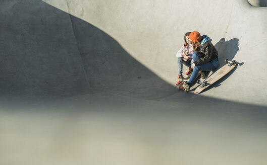 Two girls in skatepark sharing cell phone - UUF003048