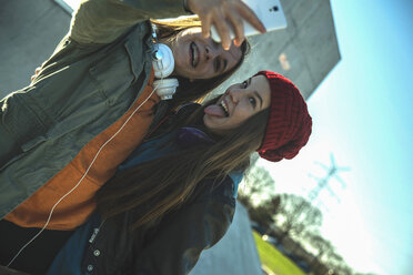 Zwei verspielte Teenager-Mädchen im Freien nehmen Selfie - UUF003081