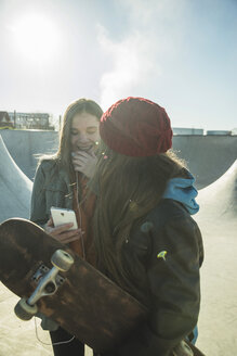 Two happy teenage girls with cell phone in skatepark - UUF003082