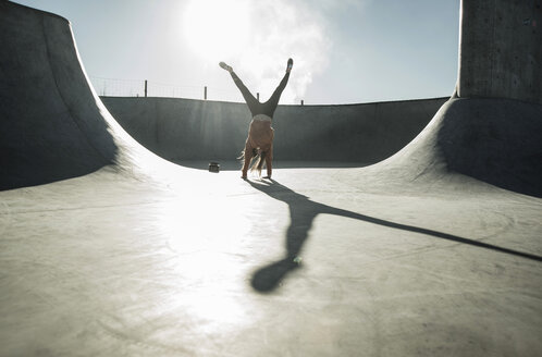 Teenage girl doing a cartwheel in skatepark - UUF003067