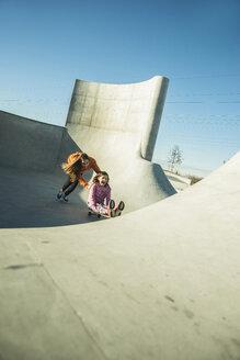 Teenage girl pushing girl on skateboard - UUF003085