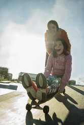 Teenager schiebt Mädchen auf Skateboard - UUF003086