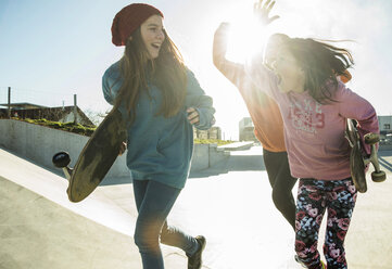 Three girls running in skatepark - UUF003077