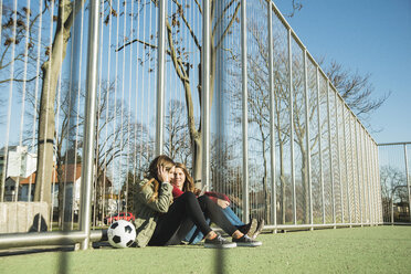 Zwei Teenager-Mädchen auf dem Sportplatz teilen sich ein Mobiltelefon - UUF003073