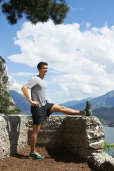 Italien, Trentino, Jogger beim Stretching am Gardasee - MRF001474
