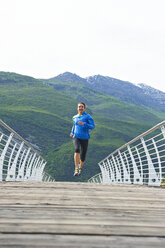 Italien, Trentino, Frau läuft auf Fußgängerbrücke in der Nähe des Gardasees - MRF001482