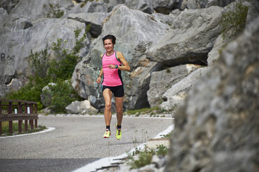 Italy, Trentino, woman running on road near Lake Garda - MRF001500