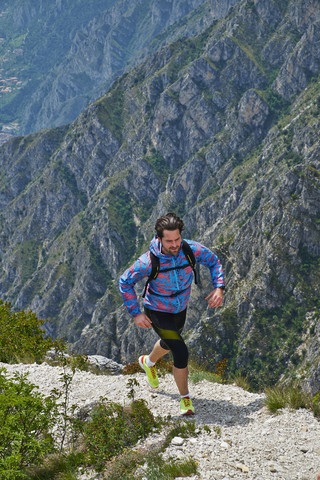 Italien, Trentino, Mann beim Berglauf am Gardasee, lizenzfreies Stockfoto