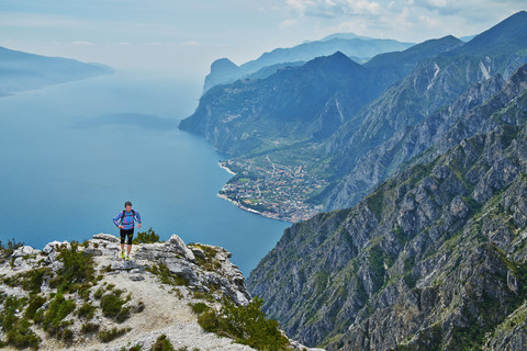 Italien, Trentino, Mann läuft auf Berggipfel am Gardasee, lizenzfreies Stockfoto