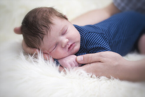 Väterliche Hände halten schlafendes Baby - ROMF000046