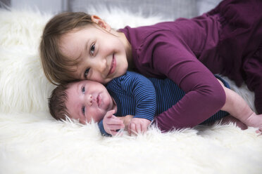 Smiling little girl with newborn brother on sheepskin - ROMF000044