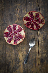 Two halves of a pomegranate and tea spoon on wood - LV002621