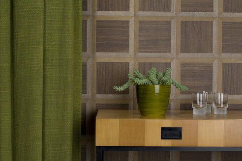 Sideboard with glasses and potted plant in front of wooden wall cladding - PATF000025