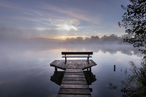 Deutschland, Bayern, Wessling, Wesslinger See, Uferpromenade mit Holzbank im Morgennebel, lizenzfreies Stockfoto