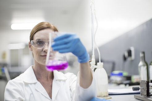 Scientist in lab holding Erlenmeyer flask - ZEF004236