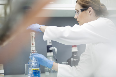 Wissenschaftlerin im Labor bei der Arbeit mit Flüssigkeit, lizenzfreies Stockfoto