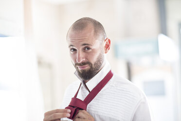 Portrait of man putting on his tie - ZEF002957
