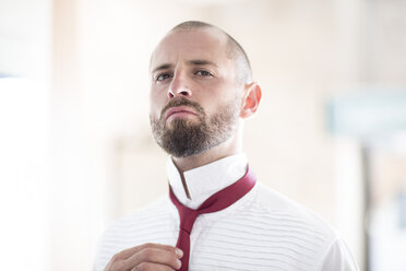 Portrait of man putting on his tie - ZEF002958