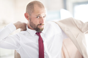 Portrait of man putting on his jacket - ZEF002962