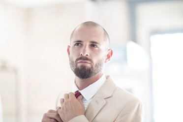 Portrait of man putting on his tie - ZEF002964