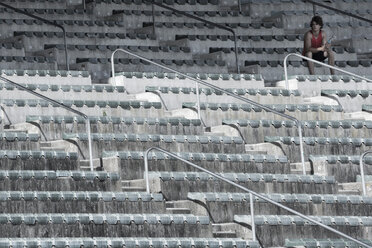 Young sportsman sitting on grandstand of a stadium - ZEF004597
