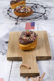 Amerikanischer Cronut mit Schokoladenglasur und Zuckerkonfetti, verziert mit der amerikanischen Flagge - ODF001054