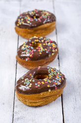 Row of three American cronuts with chocolate icing and sugar confetti - ODF001055