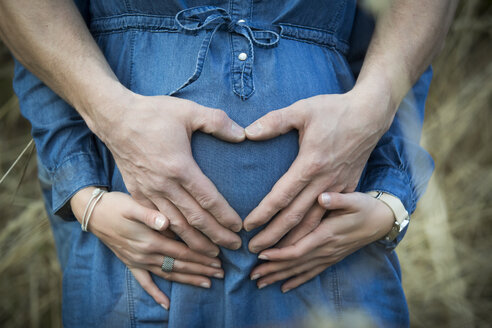Die Hand eines Mannes formt ein Herz auf dem Bauch seiner schwangeren Freundin - JTLF000042