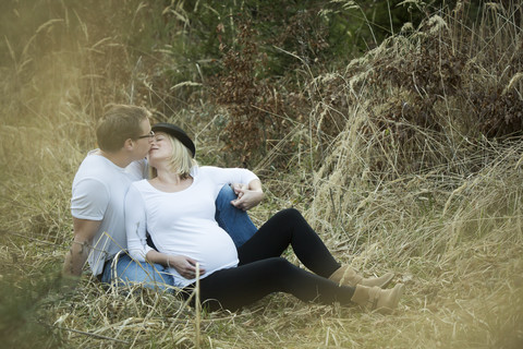 Mann küsst seine schwangere Freundin, lizenzfreies Stockfoto