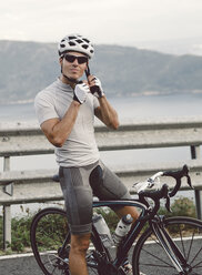 Spain, Galicia, Ferrol, male racing cyclist putting on a cycling helmet - RAEF000015