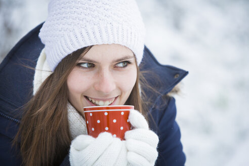 Porträt einer lächelnden jungen Frau mit Tasse im Winter - JTLF000047