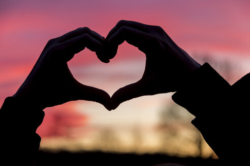 Germany, Baden-Wuerttemberg, Baden-Baden, hands shaping a heart at sunset - JUNF000191