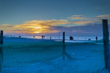 Deutschland, Niedersachsen, Norden-Norddeich, Nordseeküste bei Sonnenuntergang mit Fischernetzen am Strand - FRF000175