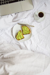 Brot mit Avocadocreme und eine Tasse Kaffee neben dem Laptop - LVF002660