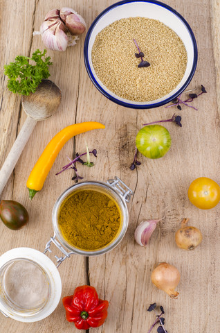 Schüssel mit Couscous, Gemüse und einem Glas Curry auf Holz, lizenzfreies Stockfoto