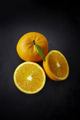 Orange und zwei Hälften einer Orange auf dunklem Grund - KSWF001348