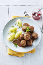 Koettbullar, schwedische Fleischbällchen mit Kartoffeln und Soße auf einem Teller, Preiselbeeren - KSWF001351