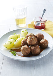 Koettbullar, schwedische Fleischbällchen mit Kartoffeln und Soße auf einem Teller, Preiselbeeren - KSWF001353