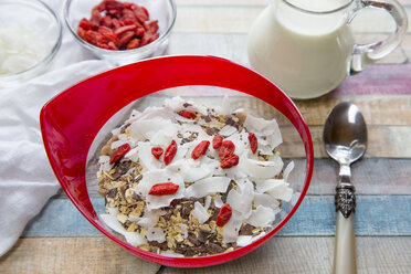 Müsli mit Chiasamen, Kokoschips, Wolfsbeeren und Milch auf Holz - SARF001274