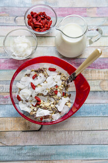 Müsli mit Chiasamen, Kokoschips, Wolfsbeeren und Milch auf Holz - SARF001278