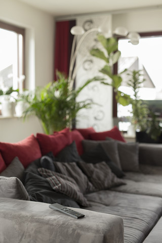 Wohnzimmer mit grauer Couch und Fernbedienung auf der Armlehne, lizenzfreies Stockfoto