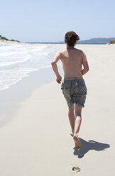 Greece, Elafonisos, young man running on sandy beach - WWF003602