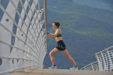 Italy, Trentino, woman stretching on bridge at Lake Garda - MRF001522