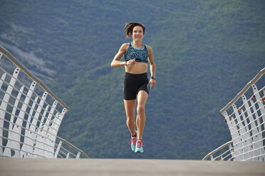 Italien, Trentino, Frau joggt auf Brücke am Gardasee - MRF001523