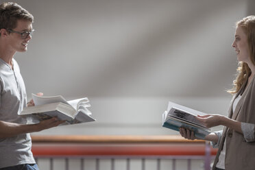 Zwei Studenten mit Büchern von Angesicht zu Angesicht in einer Bibliothek - ZEF004355