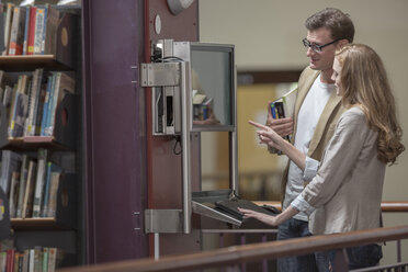 Zwei Studenten schauen auf einen Bildschirm in einer Bibliothek - ZEF004358